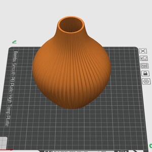 May include: An orange vase with a textured, ribbed design. The vase has a rounded body and a narrow, cylindrical neck. The vase is sitting on a black and gray grid.