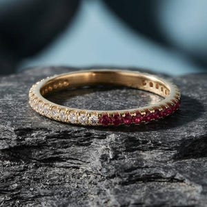 Könnte beinhalten: Ein schmaler Ring mit Pavé-Fassung und geteiltem Design. Eine Hälfte des Rings ist mit klaren weißen Steinen besetzt, während die andere Hälfte mit leuchtend roten Steinen versehen ist, was für eine zweifarbige Optik auf dem Metallband sorgt.