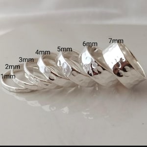 May include: A selection of silver rings, varying in width from 1mm to 7mm. The rings feature a hammered finish, giving them a textured appearance. The rings are arranged on a light-toned surface.