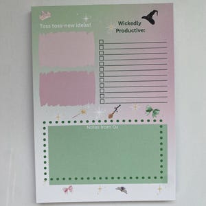 May include: A notepad with a green and pink gradient background. The notepad has the text "Toss toss-new ideas!" and "Wickedly Productive:". It also features a witch hat, a wand, and a bow. The bottom section says "Notes from Oz".