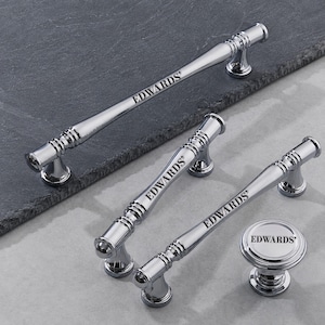 May include: A collection of polished chrome cabinet hardware including three elongated bar pulls and one circular knob. Each piece features a ribbed design at the ends and the brand name EDWARDS engraved in black lettering on the centre surface.