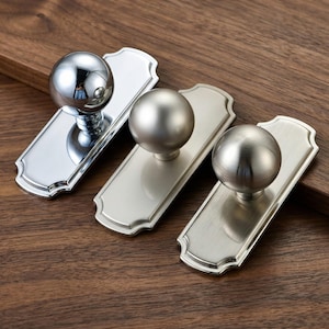 Può includere: Una tazza di ceramica bianca con manico nero e la scritta "But First, Coffee" in grassetto nero. La tazza è appoggiata su una superficie di legno. La tazza è alta 10 cm.