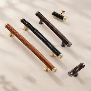 May include: A collection of cabinet hardware including three long bar pulls and two small knobs. The pulls and knobs feature a braided leather texture in tan, black, and dark brown, accented with metallic gold or dark metal end caps marked with an R.