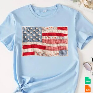 May include: Light blue t-shirt featuring a patchwork American flag design. The flag includes denim stars, red and white floral and gingham stripes, and a white border. The shirt has short sleeves and a round neckline.
