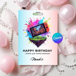 May include: A birthday card with a colorful design featuring a video game console on a floating island. The card has the text "Happy Birthday" and "Another year Another adventure" with the name "Noah's" below. Pink balloons and pearl necklaces surround the card.