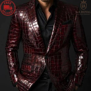 Op de afbeelding: Een bordeauxrode blazer met een krokodillenleerpatroon. De blazer heeft een revers, een sluiting met één knoop en een pochet. De afbeelding bevat ook de tekst "LA ROYAL LEATHER COMPANY".