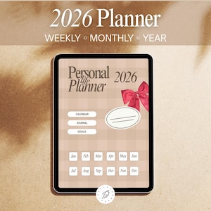 Peut inclure: Un agenda numérique pour 2026 affiché sur une tablette. L'écran affiche le texte "2026 Planner" et "Personal Life Planner". Comprend des sections calendrier, journal et objectifs, avec une mise en page mensuelle. Un nœud rouge est inclus.