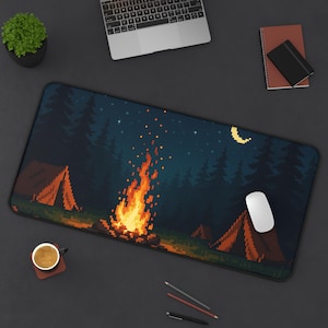May include: A rectangular desk mat with a pixelated camping scene. The design shows a campfire, tents, trees, a crescent moon, and stars against a dark blue backdrop. A computer mouse sits on the mat, with a laptop, coffee cup, and notepad nearby.