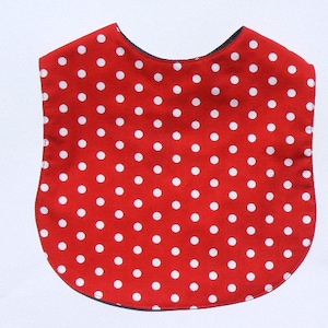 Pode incluir: Babador de tecido vermelho com bolinhas brancas.