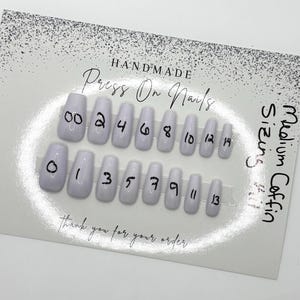 May include: A set of handmade press-on nails in a medium coffin shape. The nails are a light lavender color and are numbered 00 through 14. The card reads "Thank you for your order."