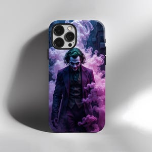 May include: A phone case featuring a digital illustration of the Joker character. The Joker is depicted in a purple suit, with green hair and white face paint, standing in front of a cloud of pink smoke. The case has a dark blue border.