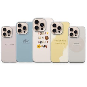 Pode incluir: Uma coleção de cinco capas de telemóvel com vários designs e citações inspiradoras. As capas apresentam uma borda transparente e uma variedade de cores, incluindo rosa claro, azul, creme e amarelo. Cada capa tem um design único, com frases como "Today is a Great Day".
