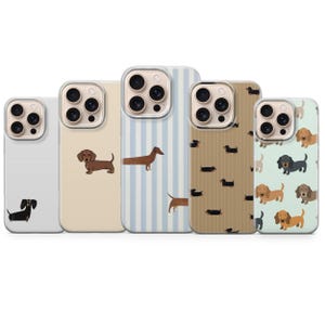 Könnte beinhalten: Fünf Handyhüllen mit Dackel-Designs. Die Hüllen weisen verschiedene Muster auf, darunter Streifen, Punkte und unifarbene Designs. Die Dackel sind in verschiedenen Farben und Posen dargestellt, was den Accessoires eine verspielte Note verleiht.