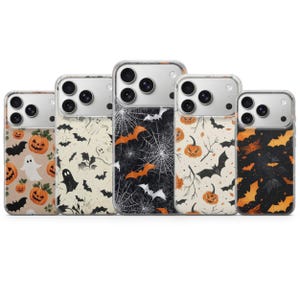Op de afbeelding: Vijf doorzichtige smartphonehoesjes met diverse Halloween-thema patronen. De ontwerpen bevatten oranje pompoenen, witte spoken, zwarte vleermuizen en witte spinnenwebben op een zwarte achtergrond. Elk hoesje heeft een uitsparing.