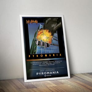 Könnte beinhalten: Gerahmtes Poster des Def Leppard Albums "Pyromania". Das Kunstwerk zeigt ein Gebäude mit einer Explosion davor. Der Albumtitel und der Bandname sind fett dargestellt. Das Poster lehnt an einer Holzoberfläche.