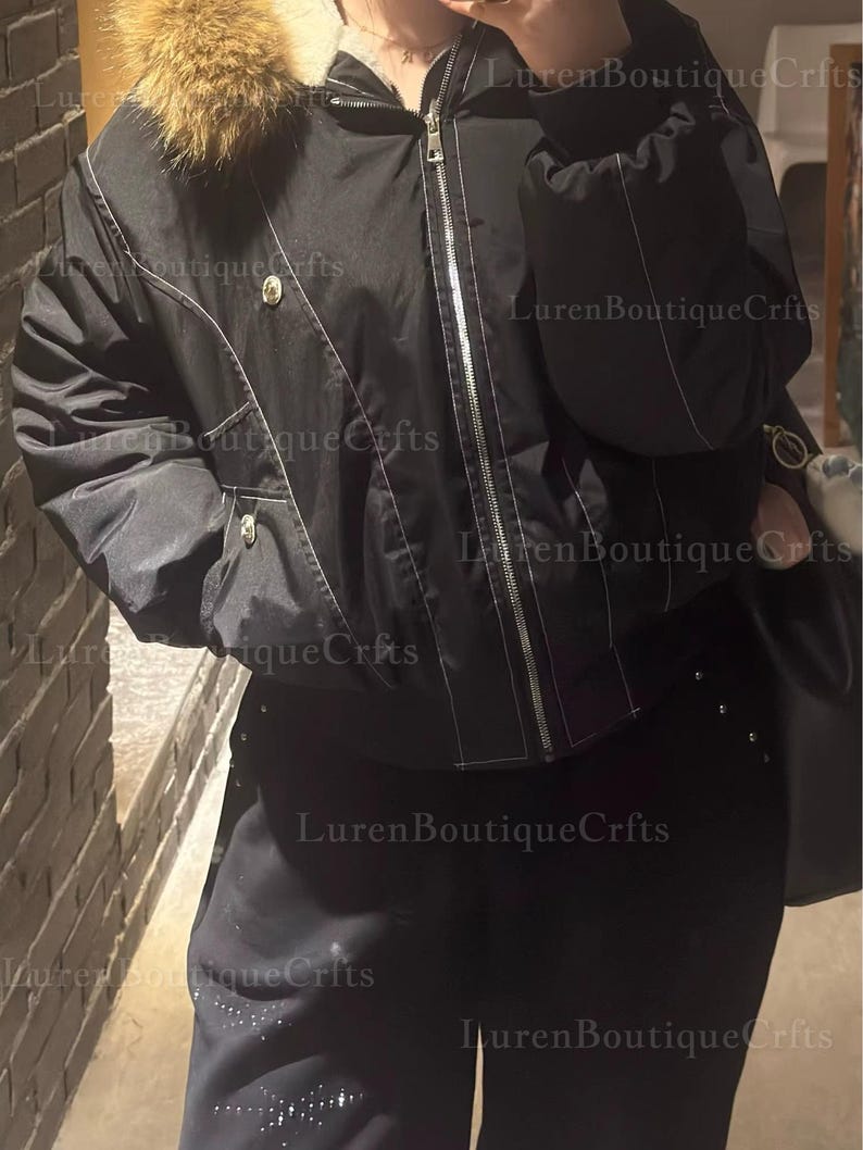 May include: Black bomber jacket with a fur-trimmed hood and white stitching details. The jacket features a zipper closure and two front pockets. The pants are black with decorative studs. The image has the text "Luren Boutique Crfts".