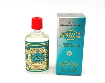 Puede incluir: Una botella de vidrio transparente de 4711 Original Eau de Cologne con una tapa roja, junto a una caja turquesa y plateada. La botella y la caja presentan etiquetas doradas y turquesas con el texto "4711" y "Echt Kölnisch Wasser".