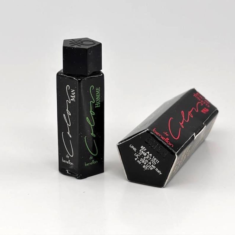May include: Two black perfume bottles with the text "Colors" and "Man" and "Homme" in green and white. The box next to the bottle has the text "Colors" in red.