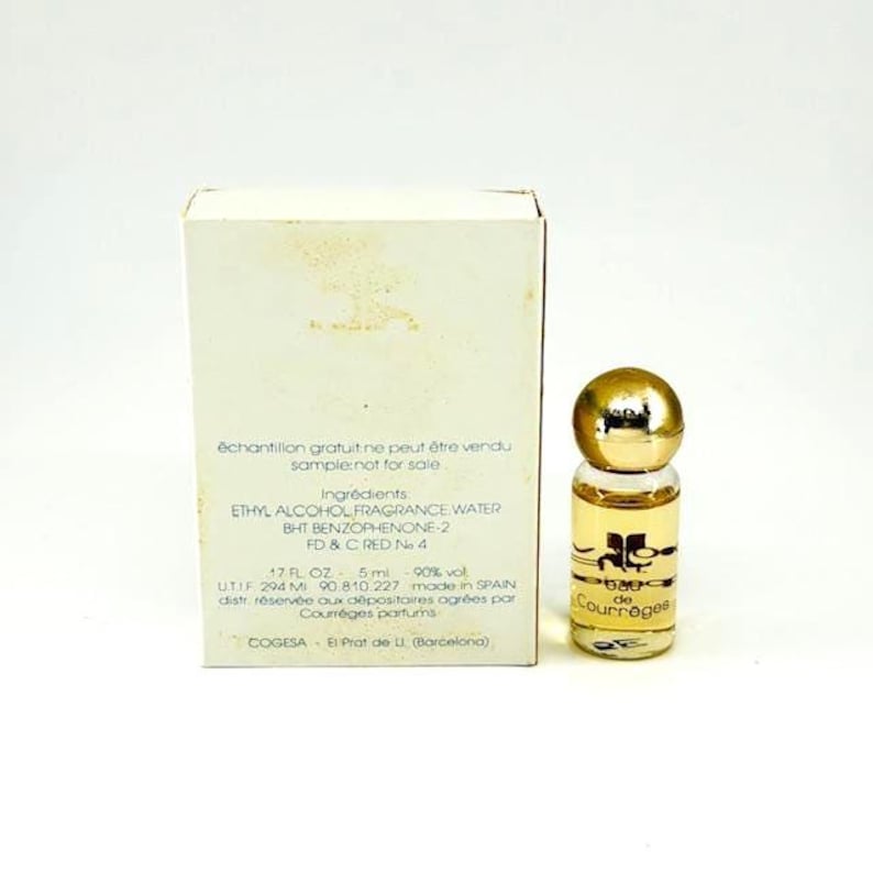 Puede incluir: Un peque&ntilde;o frasco de perfume con tap&oacute;n dorado y cuerpo de cristal transparente, junto a una caja blanca con texto en franc&eacute;s. El frasco contiene un l&iacute;quido &aacute;mbar claro y la marca "Courr&egrave;ges" es visible.