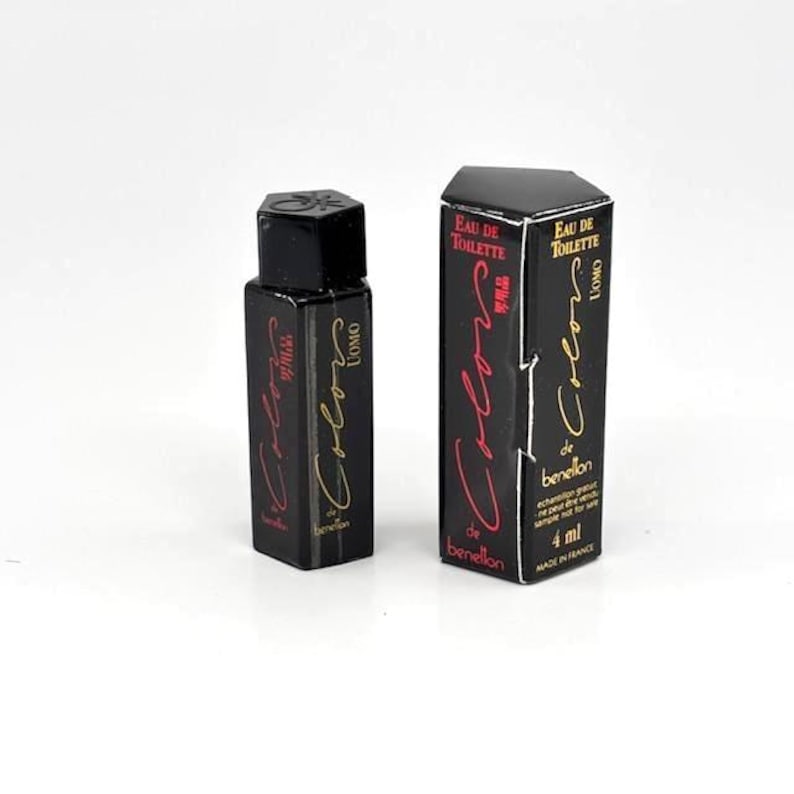 May include: A black perfume bottle and box set. The bottle and box are labeled "Colors de Benetton Uomo" with red and gold lettering. The box indicates the perfume is 4 ml.
