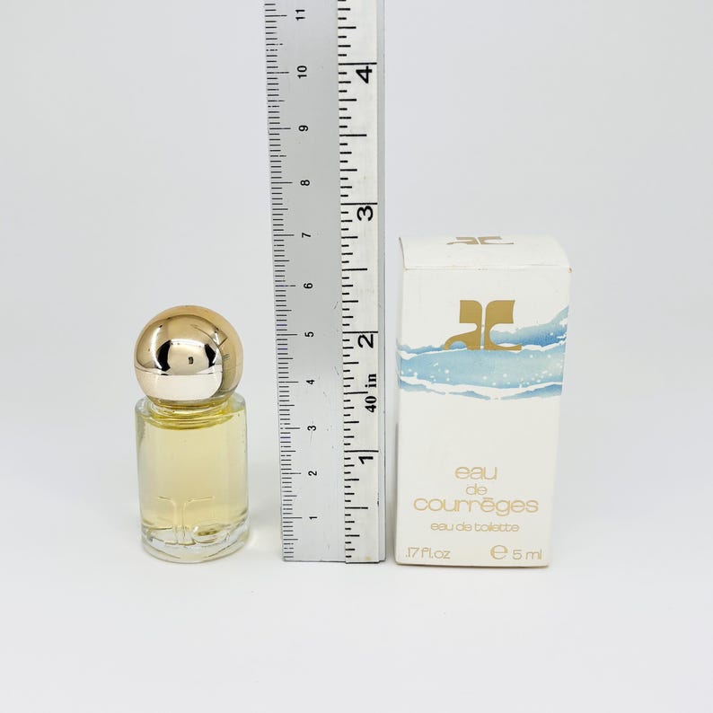 May include: A small perfume bottle with a gold cap and a clear glass body, next to a white box with the text "eau de courr&egrave;ges eau de toilette". The bottle is approximately 2 inches tall.