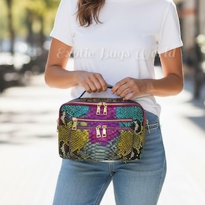 May include: A colorful, rectangular handbag with a snakeskin pattern in shades of teal, purple, yellow, and black. The bag has two zippered compartments with gold-colored zippers and a small handle. The text "Exotic Bags World" is visible on the shirt.