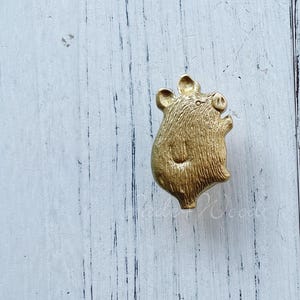 以下が含まれることがあります： 金色の金属製のブタの置物。細部まで丁寧に作られています。ブタは後ろ足で立ち、前足を上げています。