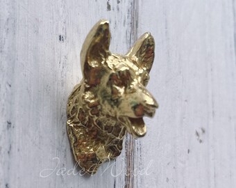 May include: Gold-toned metal dog head wall hook. The dog's mouth is open and its ears are perked up.