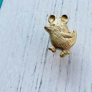 May include: A gold-colored metal mouse figurine door knob. The mouse is standing on its hind legs with its tail curled up.