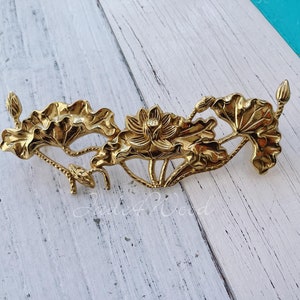 Op de afbeelding: Gouden metalen lotusbloem ontwerp. Het ontwerp heeft drie lotusbloemen met bladeren en stengels.