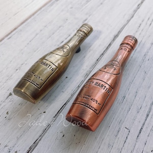 May include: Two decorative bottle stoppers shaped like miniature bottles of Remy Martin liquor. One is gold and the other is copper.