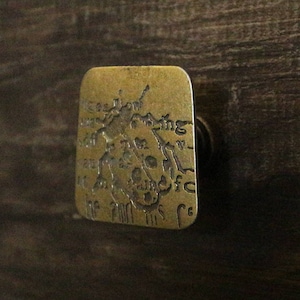 May include: A brass door knob with an intricate design featuring a skull and crossbones. The knob is engraved with the words "The Skull and Crossbones".