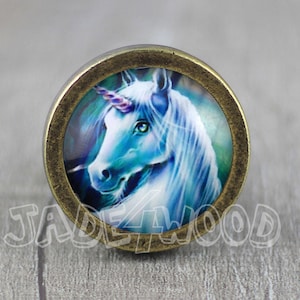 May include: A round, bronze-coloured, decorative knob with a glass insert featuring a blue and white unicorn with a purple horn.