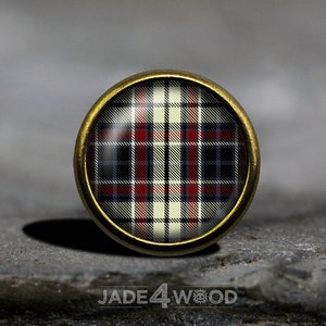 Op de afbeelding: Een ronde, gouden knop met een rood, wit en blauw ruitpatroon.