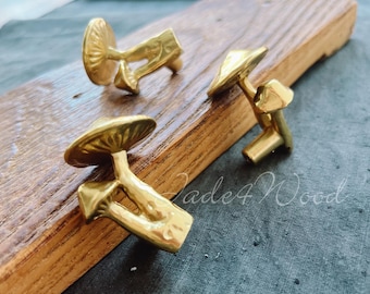 May include: Three gold mushroom-shaped cabinet knobs. The knobs are on a wooden surface. The text "Jade4Wood" is visible in the background.