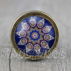 May include: A round, brass-colored cabinet knob with a blue, white, and orange geometric design.