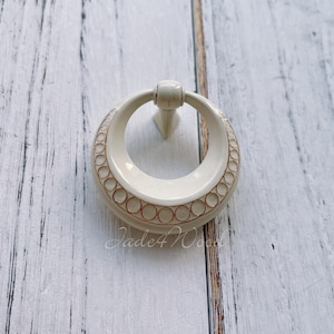 May include: White ceramic door knob with a gold ring design.