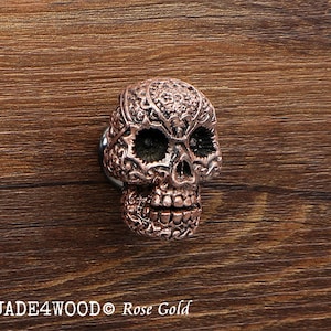 Może przedstawiać: Gałka meblowa w kształcie czaszki w kolorze różowego złota z misternymi kwiatowymi detalami. JADE4WOOD Rose Gold.