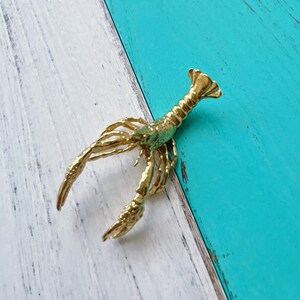 May include: A gold-colored lobster figurine with detailed claws and a textured surface.