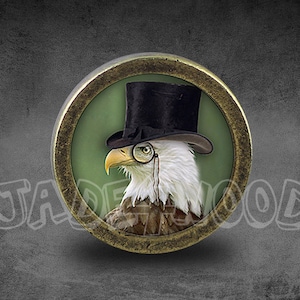 May include: A round, bronze-colored metal pin with a raised image of a bald eagle wearing a black top hat and a monocle. The eagle is looking to the left and has a green background.