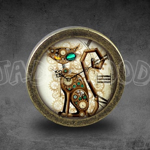 Op de afbeelding: Een ronde, messingkleurige klok met een witte wijzerplaat en een steampunk-stijl kattenontwerp. De kat is gemaakt van tandwielen en heeft een groen oog. De wijzerplaat van de klok heeft Romeinse cijfers en een tandwielontwerp.