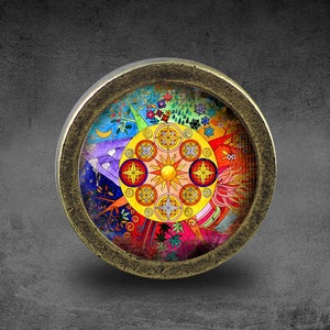 May include: A round, brass-coloured pendant with a colourful, circular design inside. The design features a sun in the centre surrounded by a mandala-like pattern with various colours, including red, yellow, blue, green, and purple.