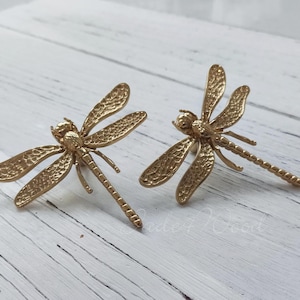 May include: Two gold-toned dragonfly drawer pulls with a textured finish.