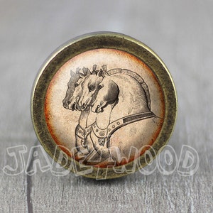 May include: Round, antique-style cabinet knob with a bronze finish. The knob features a vintage illustration of three horses' heads in profile against a faded orange and beige background. The text "JADEWOOD" is visible.