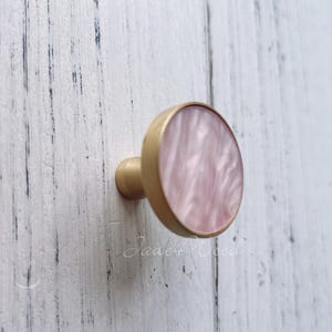 Peut inclure: Un bouton de porte rond en or et rose avec un motif en spirale.