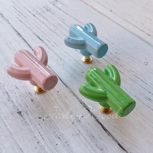 Può includere: Tre tiretti per cassetti in ceramica a forma di cactus in rosa, azzurro e verde. I tiretti hanno un design semplice e sono perfetti per aggiungere un tocco di fantasia a qualsiasi stanza.