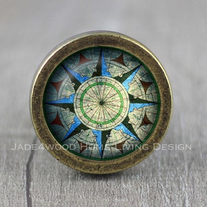 May include: A brass knob with a compass design. The compass features a blue, green, and red color scheme with a white background.
