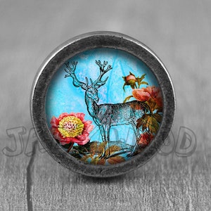 以下が含まれることがあります： ピンクの花が咲く、白黒の鹿のイラストが描かれた青と白の背景を持つ銀色のノブです。