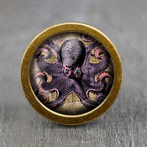 Peut inclure: Un bouton rond de couleur or avec une pieuvre violette aux tentacules roses et aux yeux verts sur un fond de style vintage.