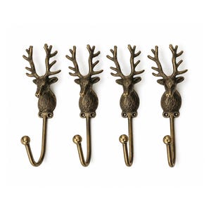 May include: A set of four wall hooks made of antique brass-coloured metal. Each hook features a detailed deer head with prominent antlers at the top and a curved hook with a rounded ball tip at the bottom, designed for mounting with two small screws.